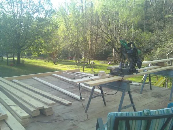 Miter saw and framing lumber on a deck under construction in Altamont